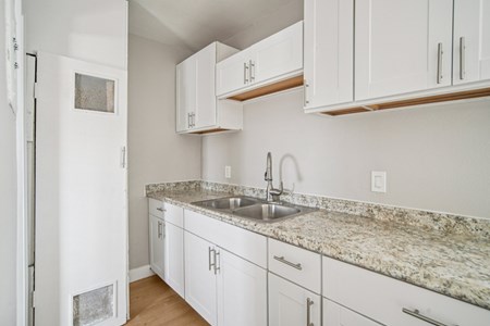 A kitchen with white cabinets and a granite countertop.
